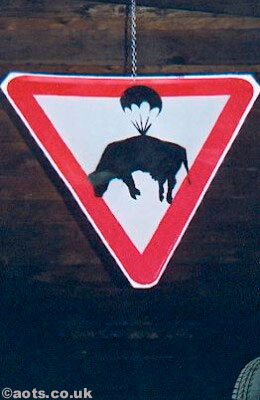 Banksy - modified sign depicting a cow and a parachute at Turf War